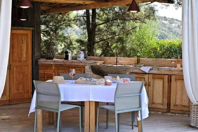 a table and chairs on a patio with a kitchen at Domaine Les Oliviers de Palombaggia in Porto-Vecchio