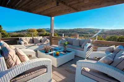 a patio with couches and a table on a deck at Chambres d'hôtes Casa di l'Oru in Porto-Vecchio