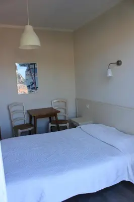 a bedroom with a white bed and a table and chairs at Hotel Cyrnos in Cargèse