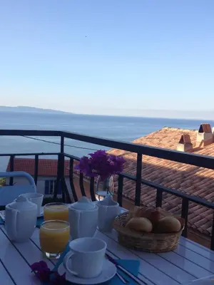 a table with food and drinks on top of a balcony at Hotel Cyrnos in Cargèse