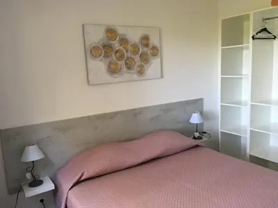 a bedroom with a bed with a pink blanket and two lamps at Thalassa in Sainte-Lucie de Porto-Vecchio