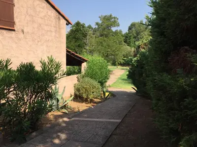 a garden path next to a building with trees at Lavu Santu in Sainte-Lucie de Porto-Vecchio