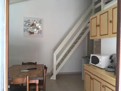 a kitchen with a dining room table and a staircase at Lavu Santu in Sainte-Lucie de Porto-Vecchio