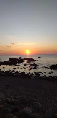 a sunset on a beach with rocks and the ocean at Lavu Santu in Sainte-Lucie de Porto-Vecchio
