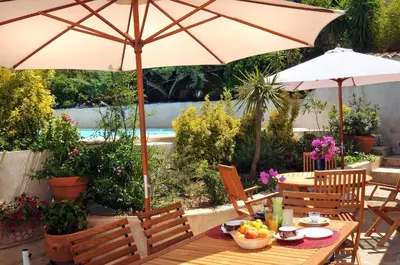 a wooden table with an umbrella and some flowers at Domaine de Saint Pierre in Cargèse