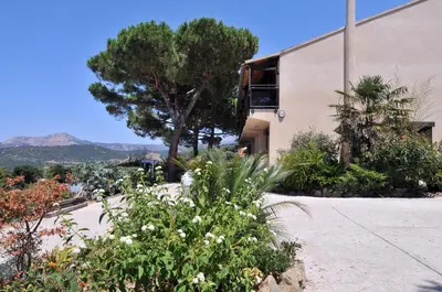 a building with trees and flowers in front of it at Domaine de Saint Pierre in Cargèse