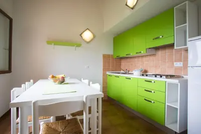 a kitchen with green cabinets and a white table at Complesso Residenziale Marina di Pinarello in Pinarellu
