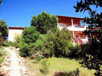 a path leading to a house with bushes and trees at Complesso Residenziale Marina di Pinarello in Pinarellu