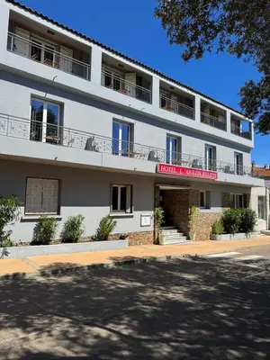 a white building with a red sign on it at L'Aiglon Bylitis in Porto-Vecchio