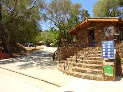 a stone building with stairs and a sign in front at Camping Mozziconaccio in Sainte-Lucie de Porto-Vecchio