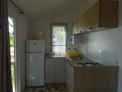 a kitchen with a white refrigerator and a sink at Camping Mozziconaccio in Sainte-Lucie de Porto-Vecchio