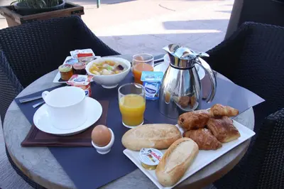 a table with a breakfast of eggs bread and orange juice at Hôtel A Madonetta in Bonifacio