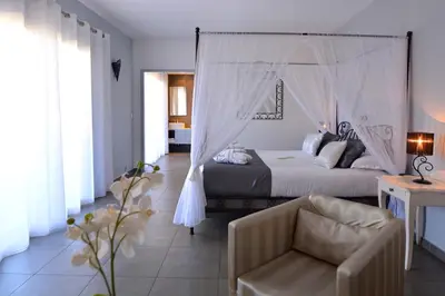 a bedroom with a canopy bed and a chair at Hôtel A Madonetta in Bonifacio