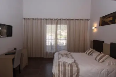 a bedroom with a bed and a desk and a window at Hôtel A Madonetta in Bonifacio