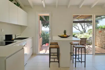 a kitchen with white cabinets and a counter with stools at Résidence Terra Marina in Bonifacio