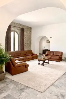 a living room with brown leather couches and a table at U Palazzu - Demeure de charme au centre de la Corse in Corte