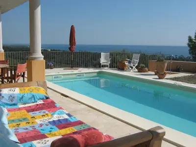 a swimming pool with a chair and a couch next to it at Gîte L'Appart de Case Vanille in Sari Solenzara