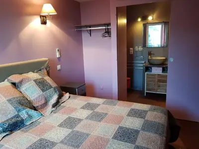 a bedroom with a bed and a bathroom with a sink at Gîte L'Appart de Case Vanille in Sari Solenzara