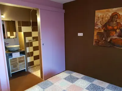 a bedroom with purple walls and a painting on the wall at Gîte L'Appart de Case Vanille in Sari Solenzara