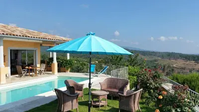 a patio with chairs and an umbrella next to a pool at Gîte L'Appart de Case Vanille in Sari Solenzara