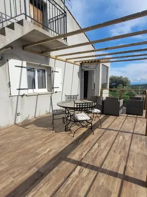 a patio with a table and chairs on a deck at Gîte Tomasini in Monacia-dʼAullène