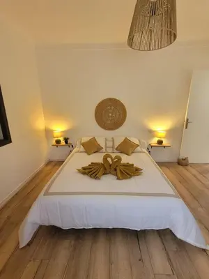 a bedroom with a large white bed with a wooden floor at Gîte Tomasini in Monacia-dʼAullène