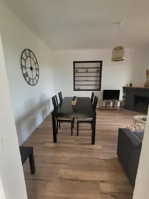a living room with a table and chairs and a clock at Gîte Tomasini in Monacia-dʼAullène