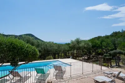 a swimming pool with chairs and a mountain at Maison Tavolara in Porto-Vecchio