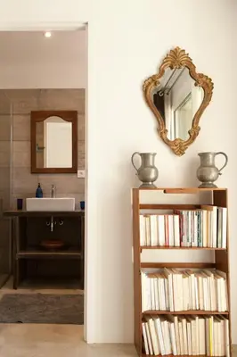 a bathroom with a sink and a mirror and a book shelf at Maison Tavolara in Porto-Vecchio