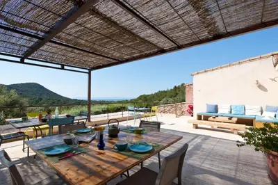 an outdoor patio with a wooden table and chairs at Maison Tavolara in Porto-Vecchio