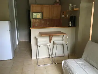 a kitchen with a table and two stools at Le Clos des Arbousiers in Linguizzetta