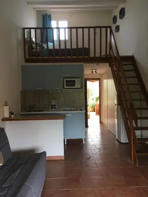 a kitchen with a staircase leading up to a loft at Le Clos des Arbousiers in Linguizzetta