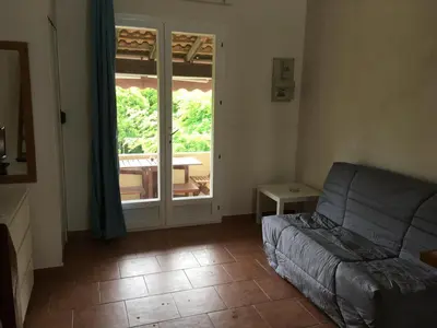 a living room with a couch and a sliding glass door at Le Clos des Arbousiers in Linguizzetta