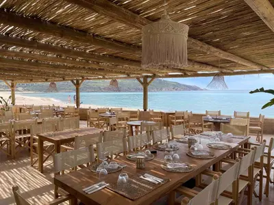 a restaurant with tables and chairs and a view of the beach at Hôtel et Résidence Ta Kladia - Omigna in Cargèse
