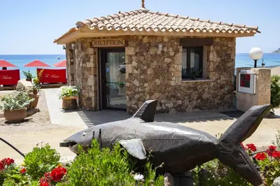 a statue of a shark in front of a building at Hôtel et Résidence Ta Kladia - Omigna in Cargèse