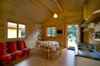 a kitchen with a table in a wooden cabin at Camping U STABIACCIU in Porto-Vecchio