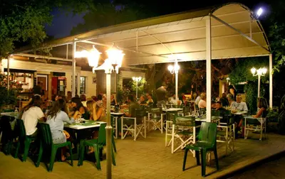 a group of people sitting at tables at a restaurant at night at Camping U STABIACCIU in Porto-Vecchio