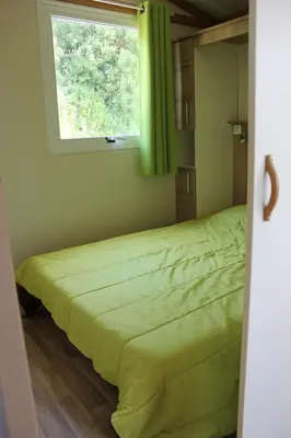a bedroom with a green bed with a window at Les Hauts de Torraccia in Cargèse