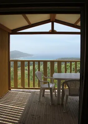 a table and chairs on a deck with a view at Les Hauts de Torraccia in Cargèse