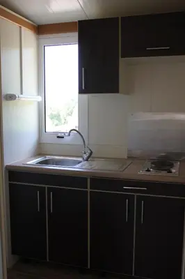 a kitchen with black cabinets and a sink and a window at Les Hauts de Torraccia in Cargèse