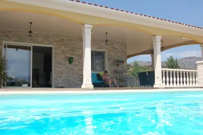 a man sitting in a chair next to a swimming pool at Perula di Machja in Alata