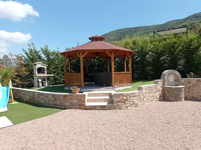 a wooden gazebo with a stone wall at Perula di Machja in Alata