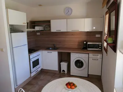 a small kitchen with white appliances and a plate of fruit on a table at Maison Alba Rossa 56 in Serra-di-Ferro