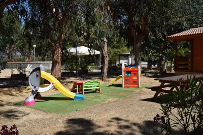 a park with a playground with a slide and a table at Camping Paradella in Calenzana