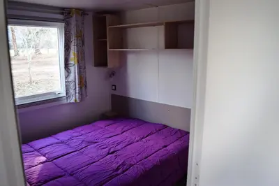 a purple bed in a room with a window at Camping Paradella in Calenzana