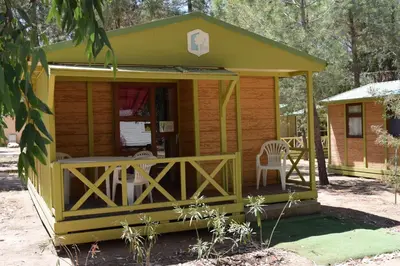 a small yellow cabin with a table and chairs at Camping Paradella in Calenzana