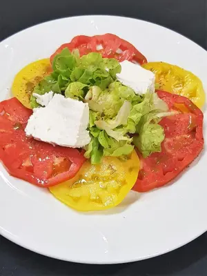 a plate of food with tomatoes and cheese and lettuce at Maison d'Hôtes Zella in Bains de Guitera