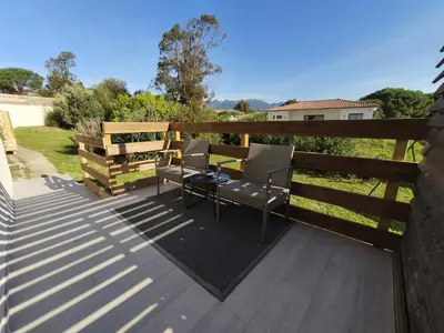 a deck with two chairs and a table and a fence at Chambres Isula Bella in Figari