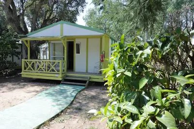 a small yellow house with a porch in a yard at CAMPING LES ILOTS D'OR in Porto-Vecchio