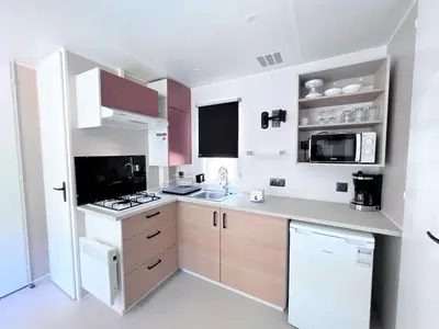 a small kitchen with white appliances and pink cabinets at CAMPING LES ILOTS D'OR in Porto-Vecchio